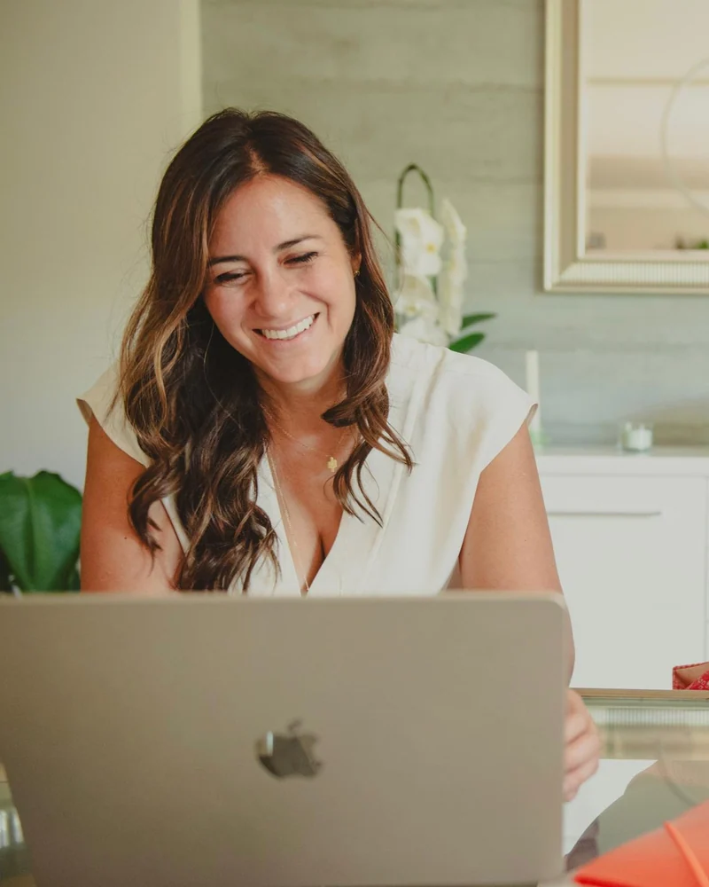 Melissa smiling while working at her laptop